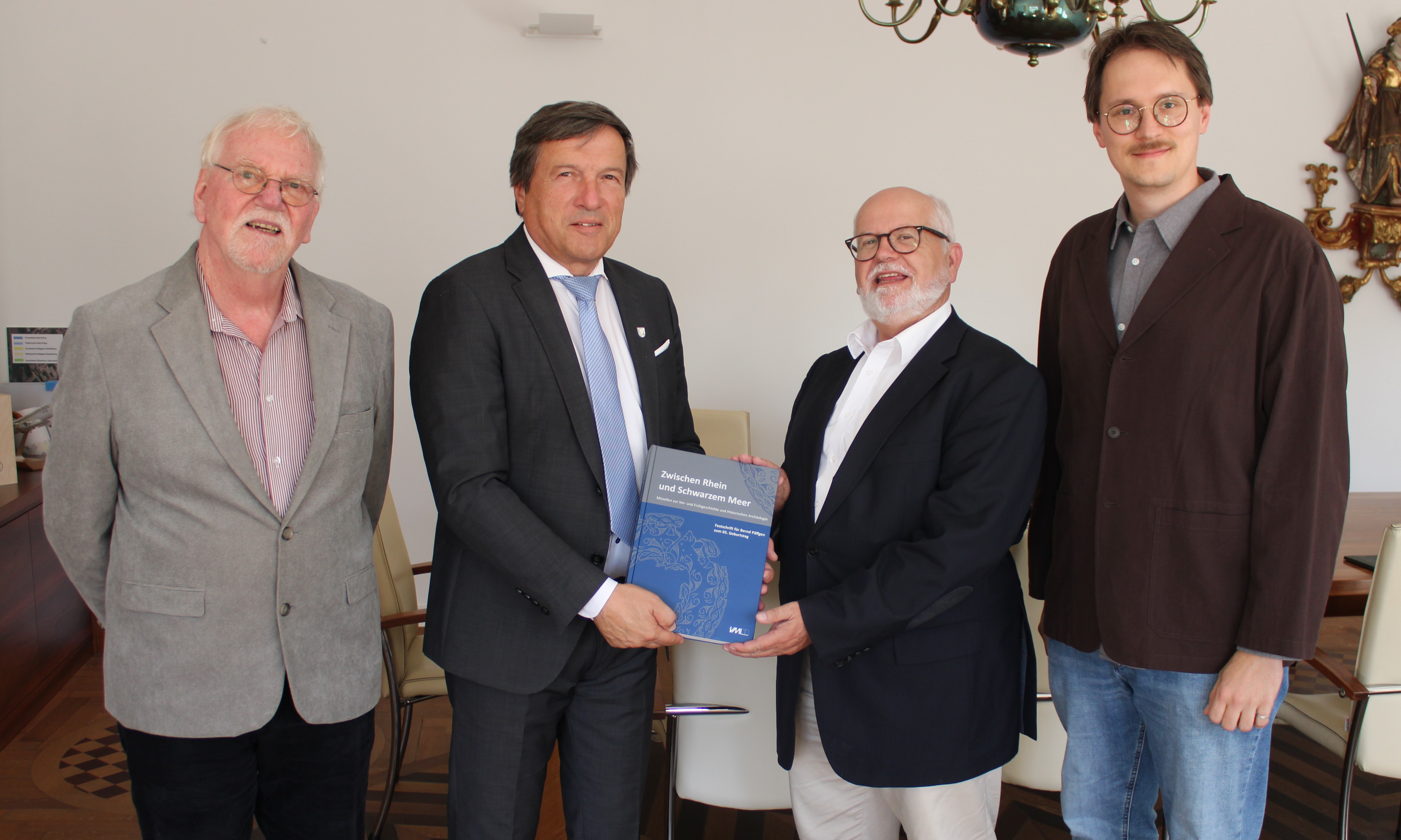 Dr. Marc Miltz (Landesamt für Denkmalpflege), Prof. Dr. Bernd Paeffgen (von rechts) sowie der Stadtheimatpfleger Archäologie Wilhelm Wagner (links) übergeben Oberbürgermeister Max Gotz das neue Buch mit Beiträgen über Erding.